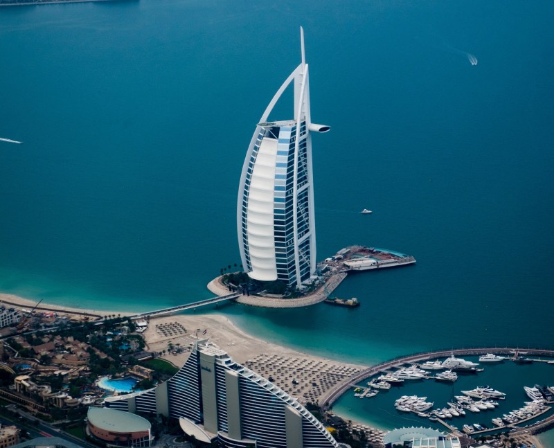 A large hotel on the beach with boats in it