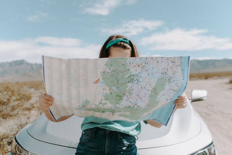 A woman holding up a map in front of her face.